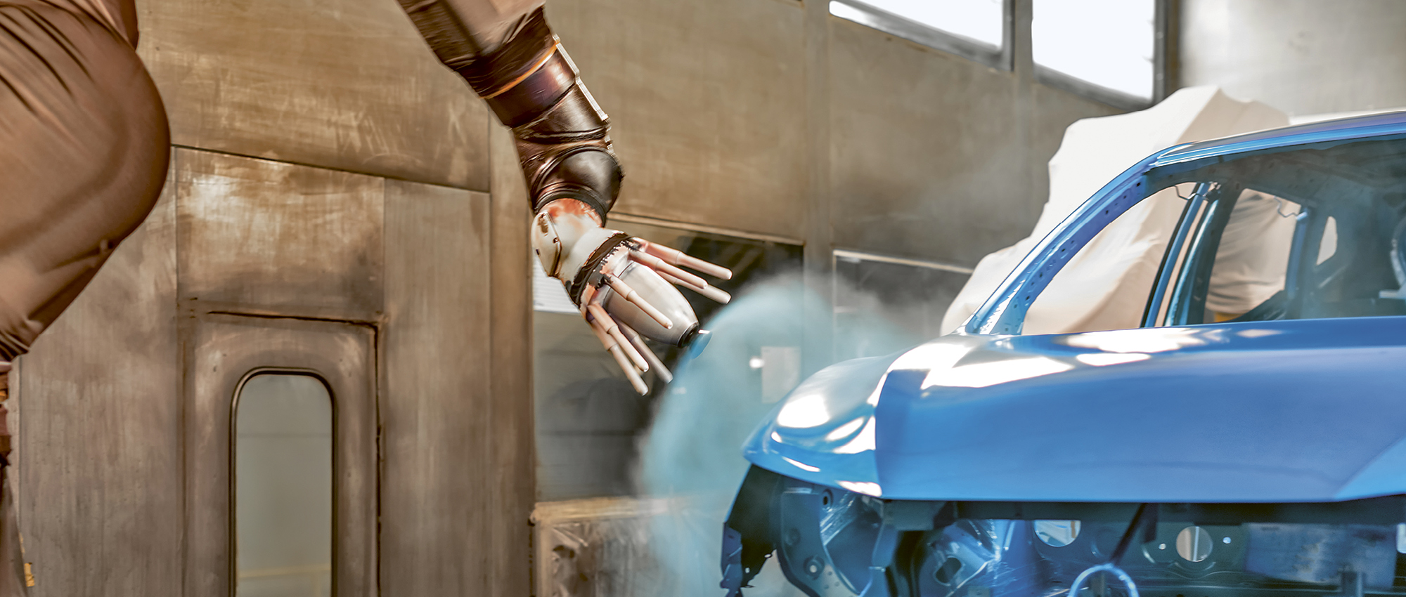Roboter-Lackierarm sprüht blaue Farbe auf eine Autokarosserie in einer Fabrik. Copyright Shutterstock /  Vadim Kulikov