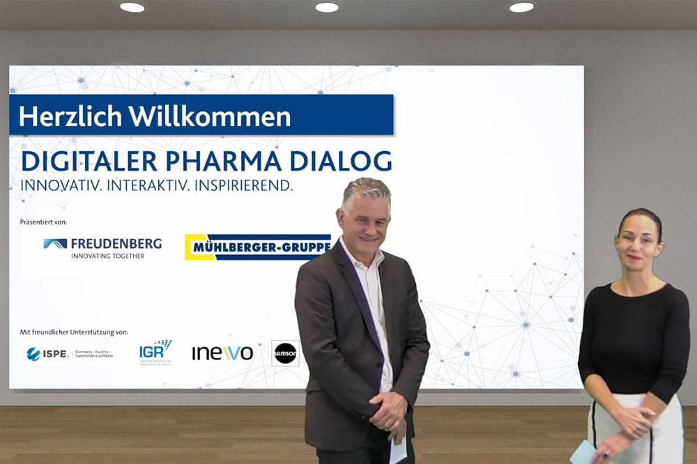 Zwei Personen stehen vor einem Präsentationsbildschirm des Digitalen Pharmadialogs.
