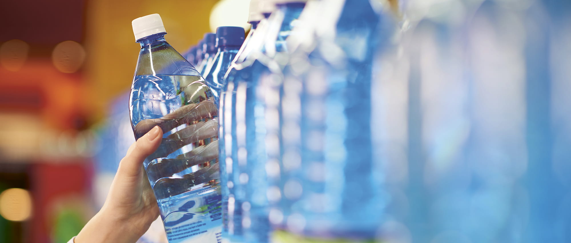 Eine Wasserflasche wird aus einem Regal gegriffen. Copyright iStock / mediaphotos