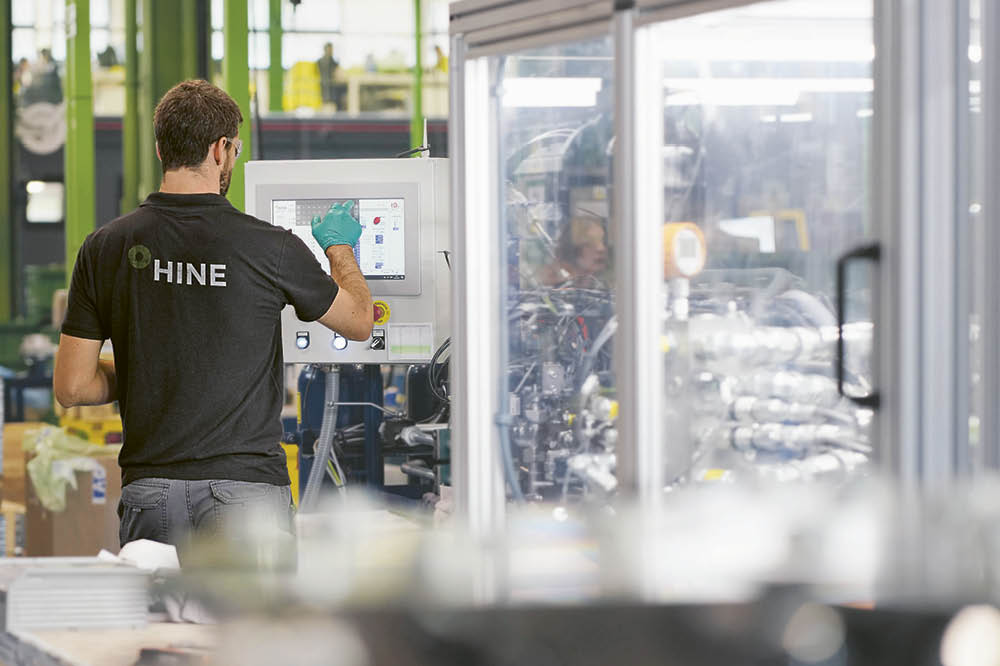 Hine Mitarbeiter betätigt eine Maschine in einer Fabrik.