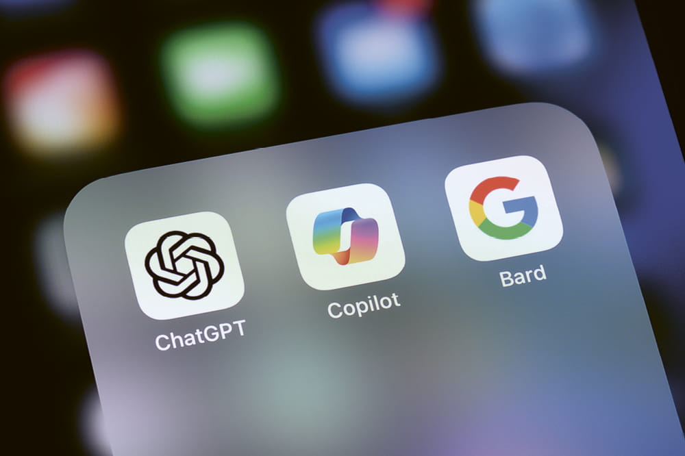 Display eines iPhone mit den Apps ChatGPT Copilot und Bard.