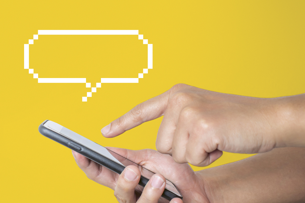 Eine Hand tippt auf einem Handy. Im gelben Hintergrund taucht eine Sprechblase auf. Copyright: iStock/Phira Phonruewiangphing