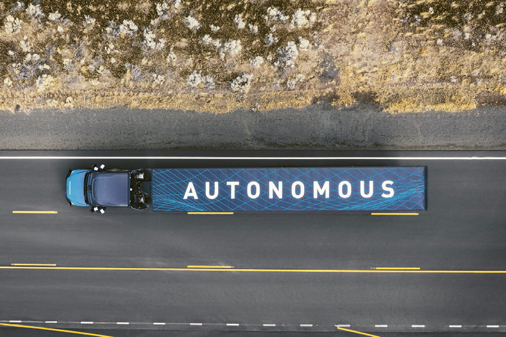 Ein LKW mit der Aufschrift Autonomous fährt auf einer Straße. 
