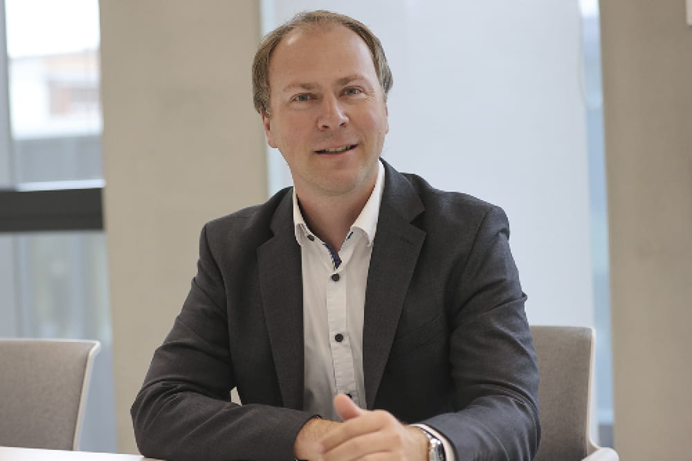 Porträt von Marcel Schreiner, der an einem Tisch sitzt. 