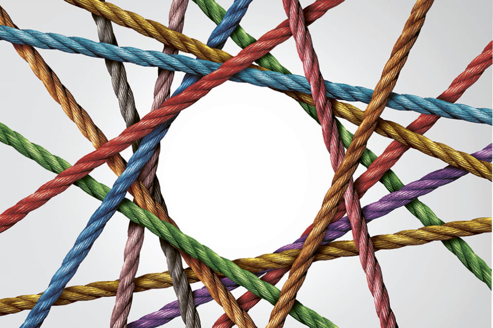 Ein Netz aus verschiedenfarbigen Seilen, die einen Kreis in der Mitte bilden. Copyright: iStock/wildpixe