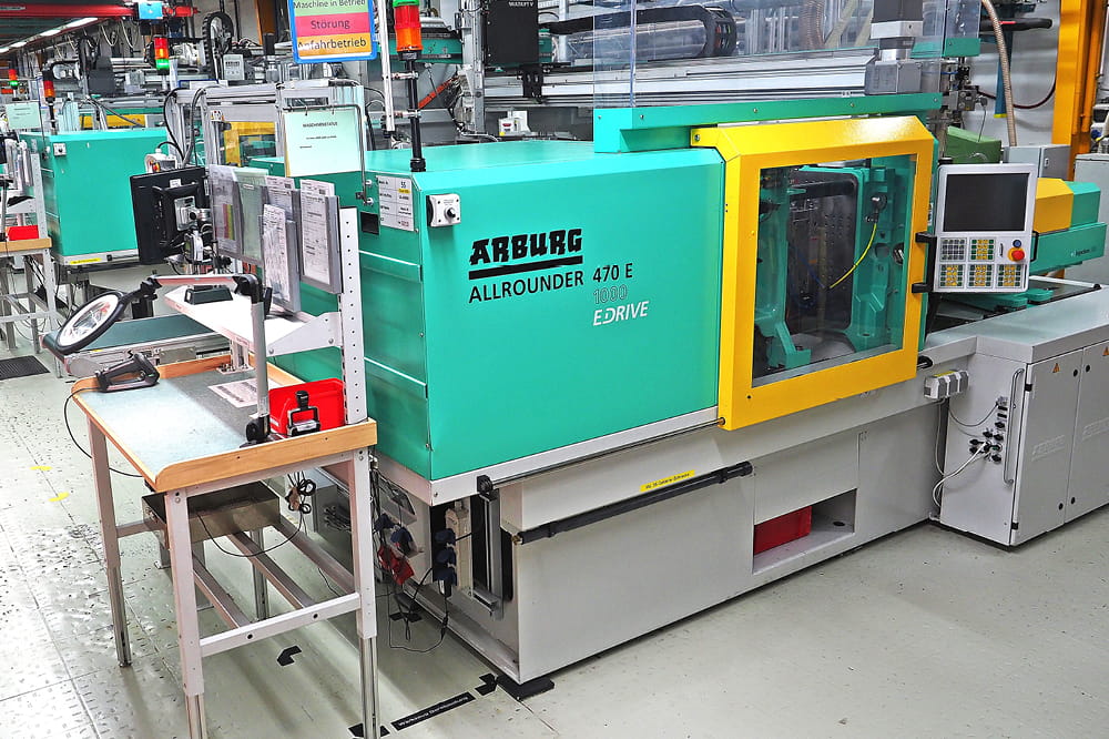 Eine grüne Maschine in einer Fabrik mit der Aufschrift Arburg Allrounder 470E.