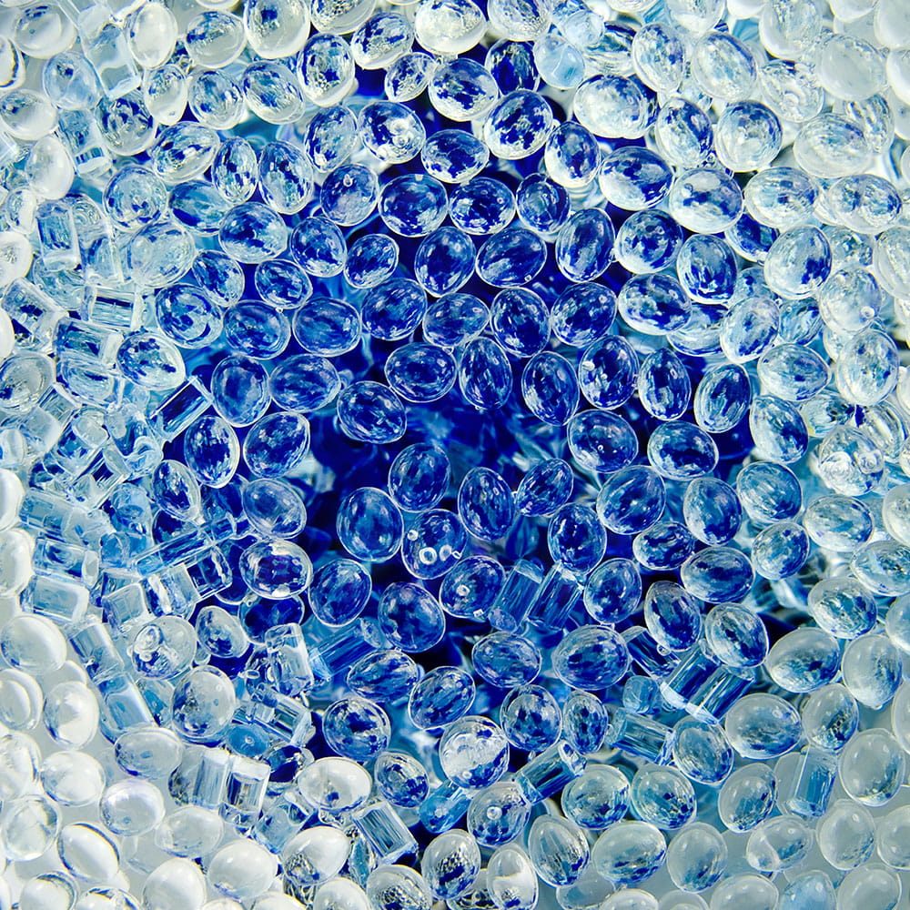 Transparent plastic polymer granules on blue background