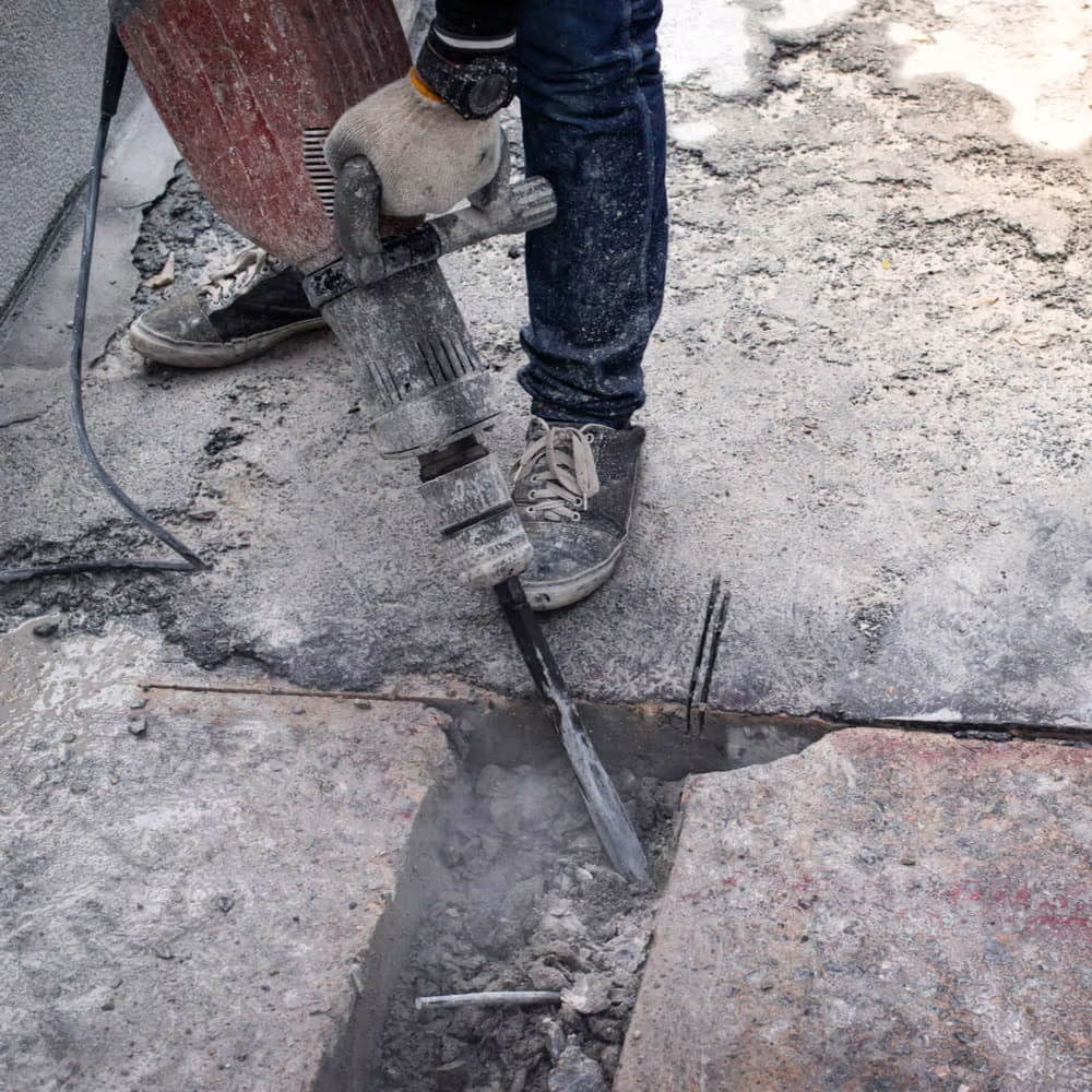Close up of a worker with jackhammer on a cement base
